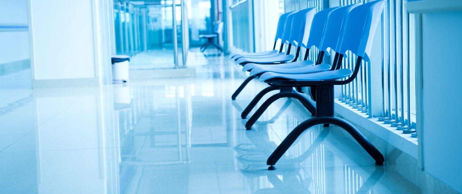 A row of chairs along a corridor with a glossy floor, in blue-toned lighting